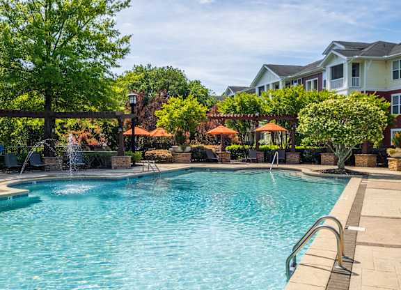 A large swimming pool surrounded by trees and a fountain.