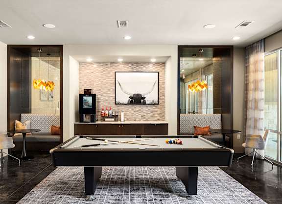 A pool table is in the middle of a room with a television and a couch.