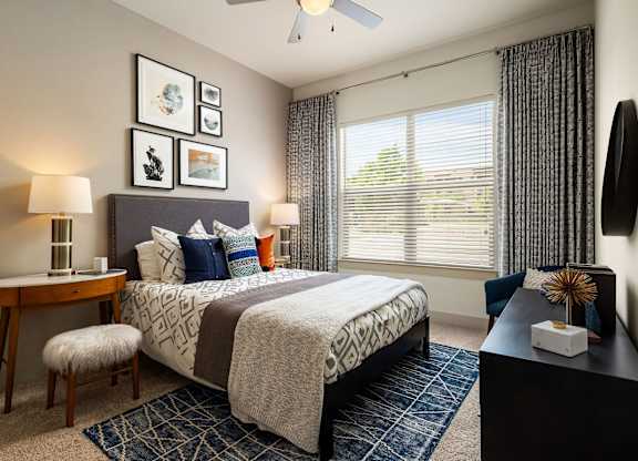 A bedroom with a bed, nightstand, and a window with blinds.