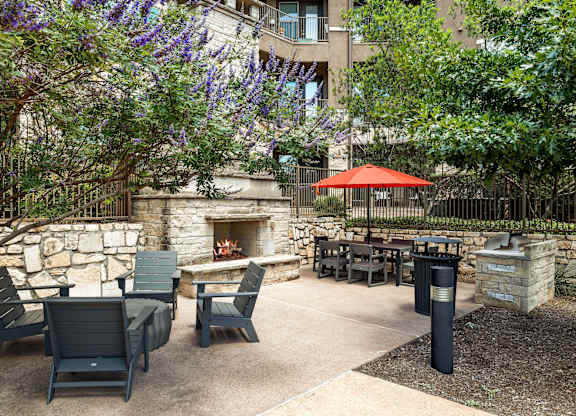 A patio with a fireplace and chairs.