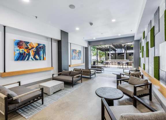 A modern living room with a large painting on the wall and a green plant on the side.