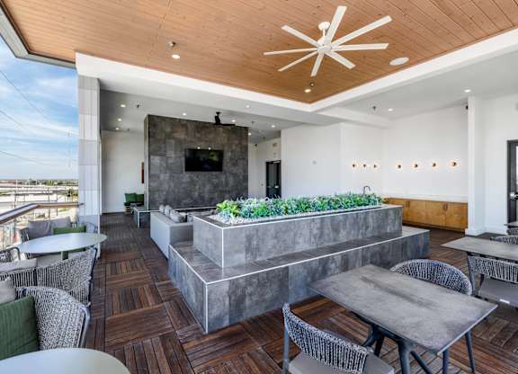 A modern outdoor patio with a wooden floor and grey furniture.