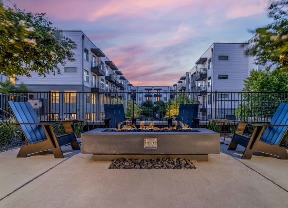 an outdoor patio with a fire pit and chairs at dusk