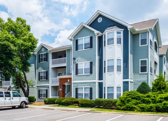 a blue and white apartment building with cars parked outside