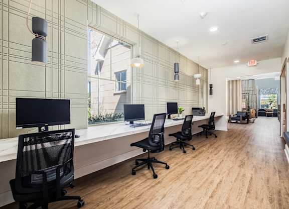 A modern office with wood floors and black chairs.