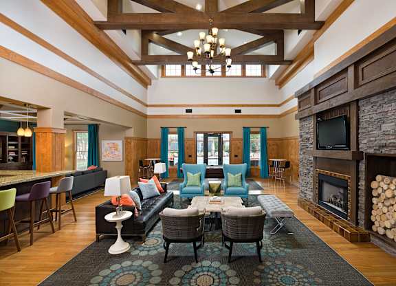 A living room with a stone fireplace and a large rug.