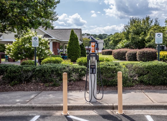 a gas pump in a parking lot with a house in the background