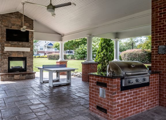 a covered patio with a fireplace and a barbecue