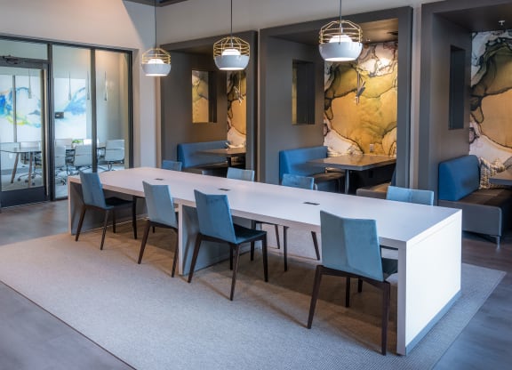 a dining room with a long white table and blue chairs