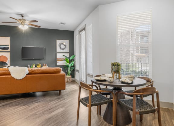 a dining area with a round table and four chairs and a couch in the background