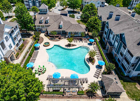 An aerial view of a swimming pool surrounded by buildings and trees.