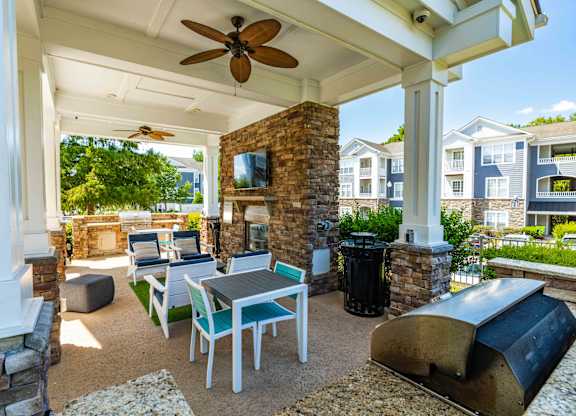 A patio with a table and chairs under a ceiling fan.
