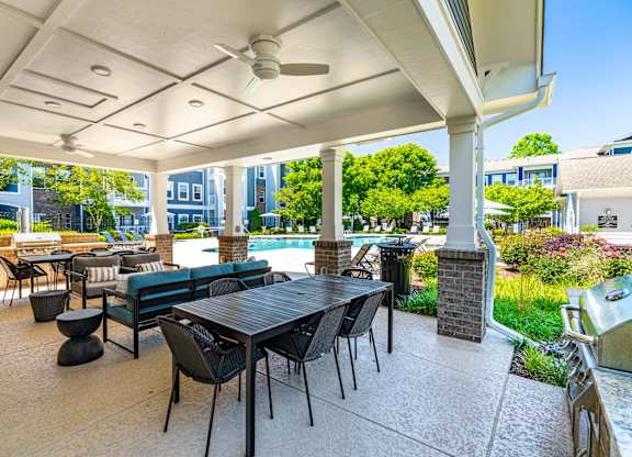 A patio with a table and chairs is covered by a roof.