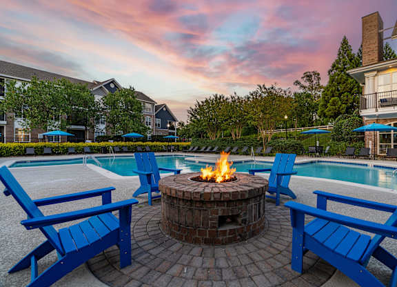 A fire pit surrounded by blue chairs in a backyard.
