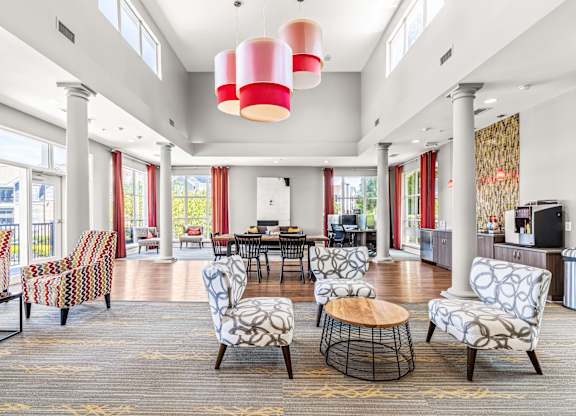 A large room with a round table and chairs with a red and white lamp hanging from the ceiling.