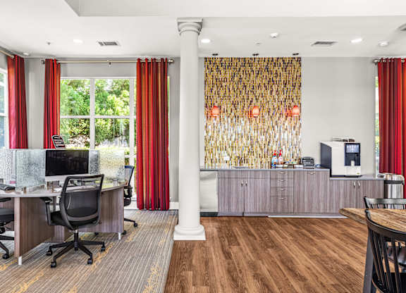A room with a desk, chairs, and a window with red curtains.