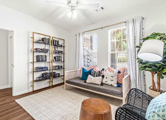 A living room with a couch, a chair, a table, a potted plant, and a bookshelf.