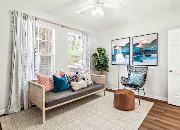 A living room with a couch, chair, and potted plant.