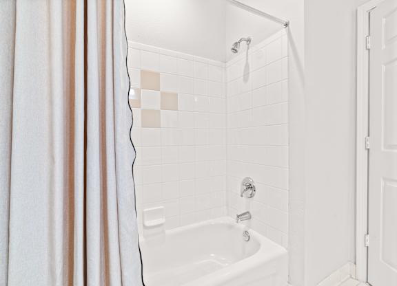 A white bathroom with a shower and a white door.
