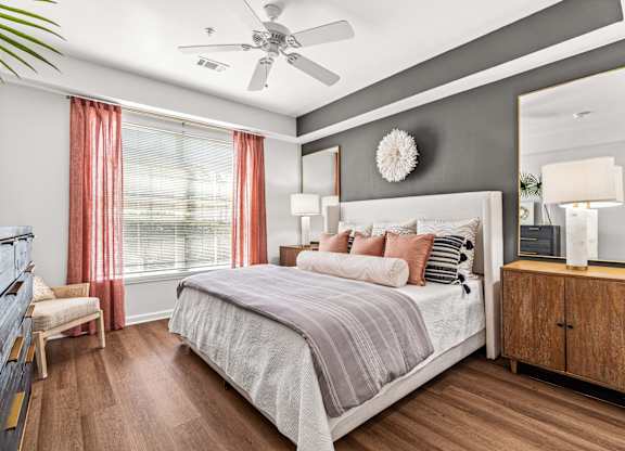 A bedroom with a large bed, a ceiling fan, and a wooden floor.