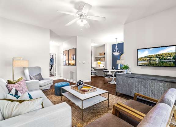 A living room with a white couch, a coffee table, and a television.