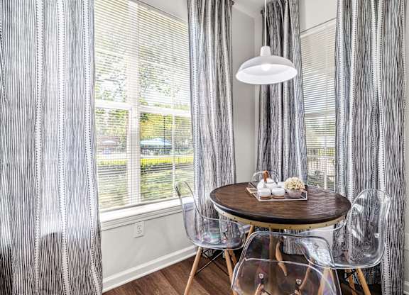 A dining room with a table set for two and a view of a backyard.