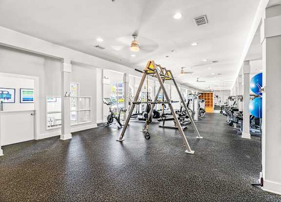 A gym with a variety of equipment including a treadmill, exercise balls, and weights.