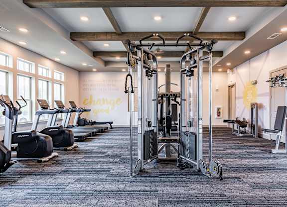 a large fitness room with cardio equipment and windows