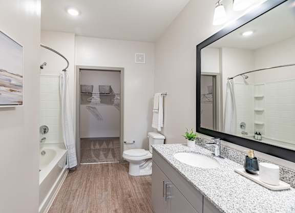a bathroom with a large mirror and a toilet next to a bathtub
