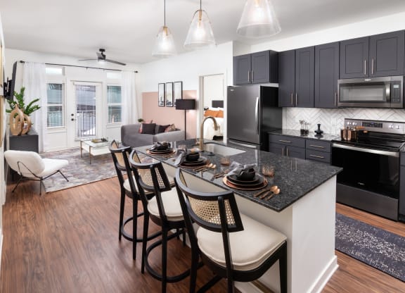 a kitchen and living room with black cabinets and a granite counter top