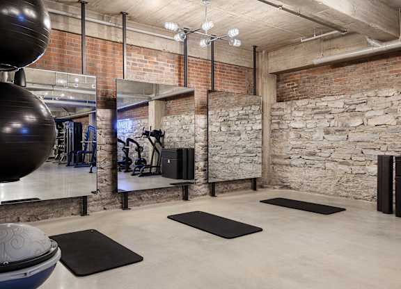 the gym has exposed brick walls and a large exercise ball and rugs