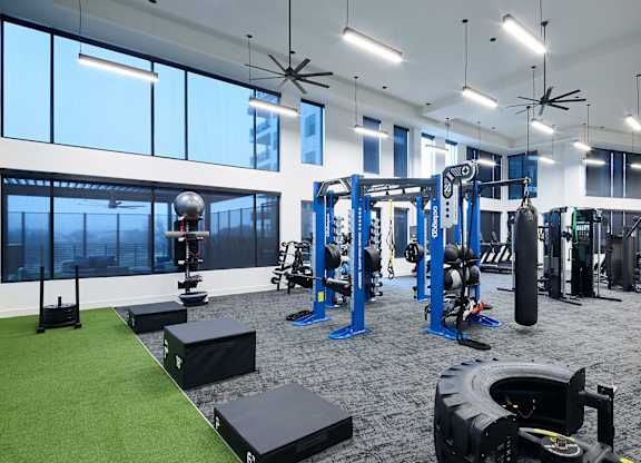 A gym with a variety of equipment including weights and a green artificial turf area.