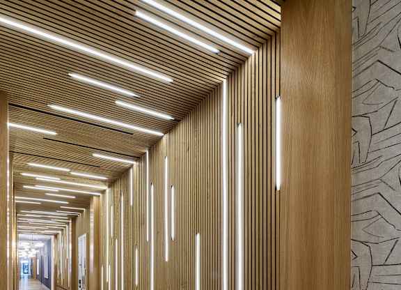 A long hallway with wood paneling and lighting on the ceiling.