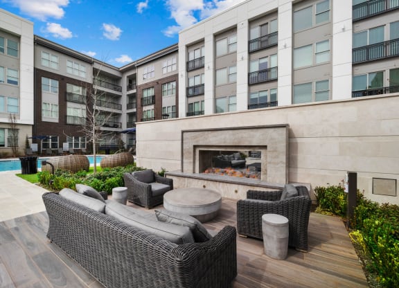 a patio with furniture and a fireplace in front of an apartment building