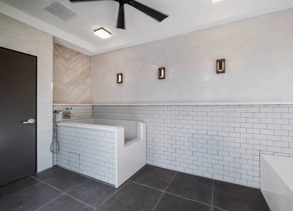 a bathroom with white tiles and a tub and a sink