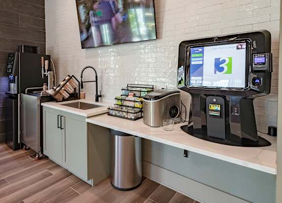 a coffee shop with a large tv on the wall and a kitchenette with a sink and