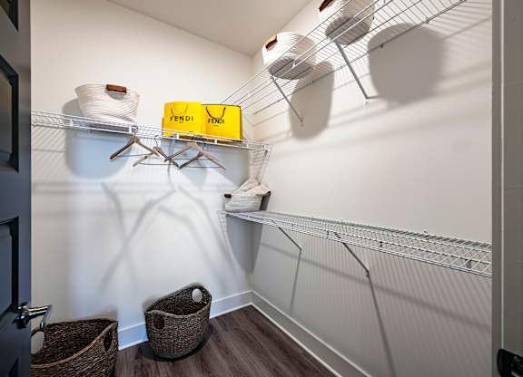 a walk in closet with white walls and a yellow box on a wire shelf