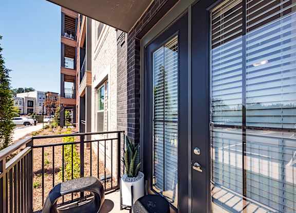 a balcony with a chair and a table with a potted plant on it
