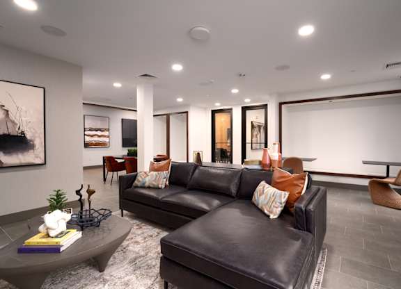 A living room with a black couch and a grey coffee table.