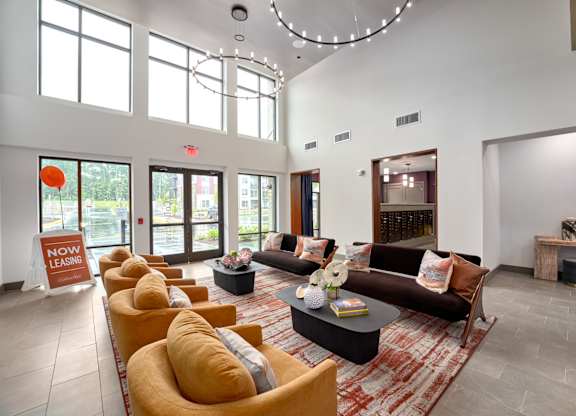 A living room with a long couch and a sign that says "Now Leasing".