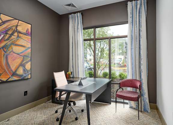 A room with a desk and a chair with a window in the background.