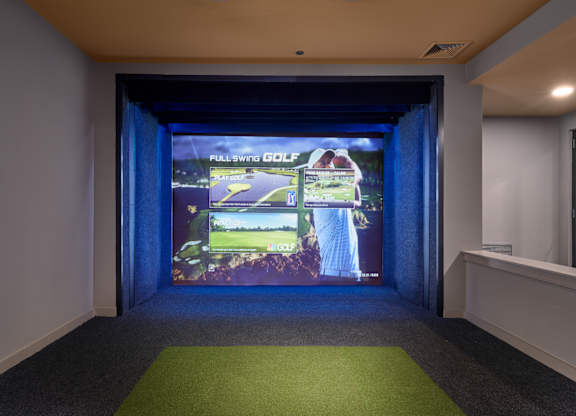 A room with a screen showing a golf game.