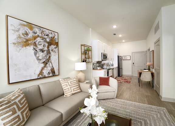 A living room with a large painting on the wall and a beige couch.