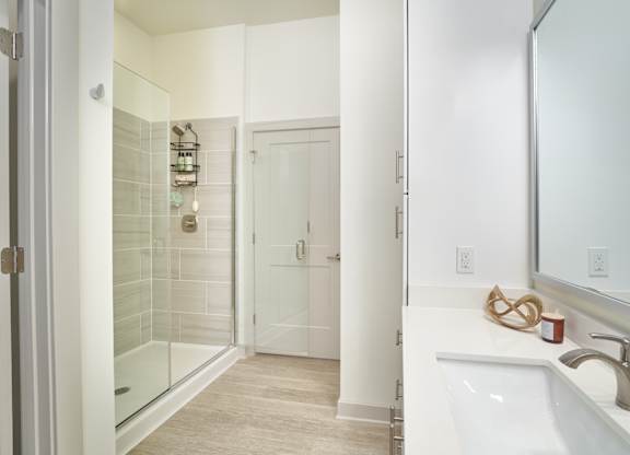 A bathroom with a white sink, mirror, and tiled shower.