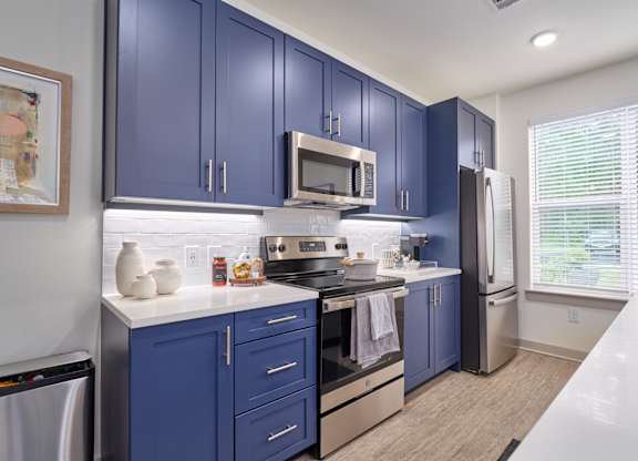 A kitchen with blue cabinets and stainless steel appliances.