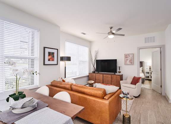 A living room with a brown sofa, a wooden table, and a television.