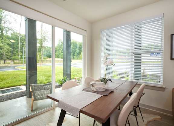 A dining room with a table and chairs and a view of the outside.