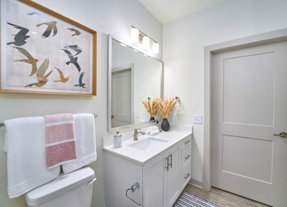 A white bathroom with a towel hanging on the toilet.