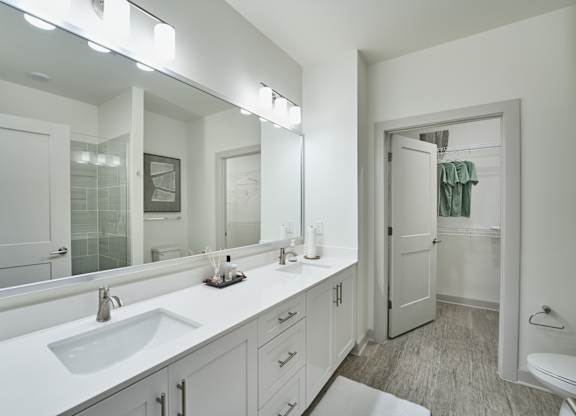 A white bathroom with a sink, mirror, and toilet.