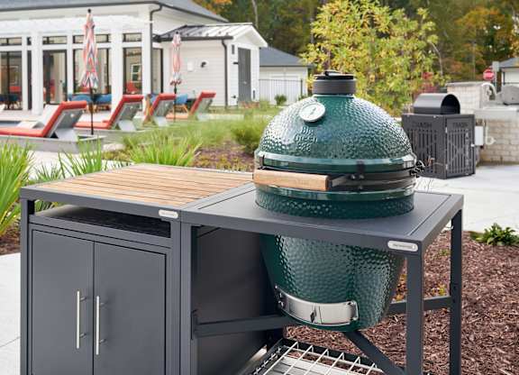 A green grill is on a table outside.